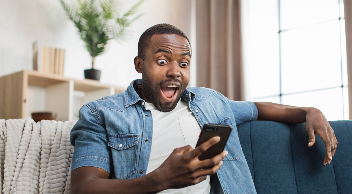 african-man-reading-good-news-on-mobile-at-home-2023-11-27-05-25-55-utc 1 (1)